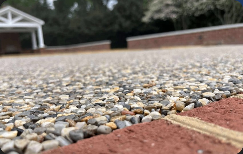 Grey Blend Stone Wrap patio — grey and tan pebble surface beside a brick border