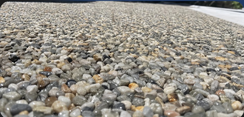 Grey Blend Stone Wrap surface — grey, white and tan pebble stone in full sun